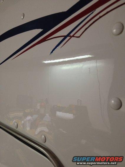 White truck side with red, white, and blue stripe graphics and visible rivets