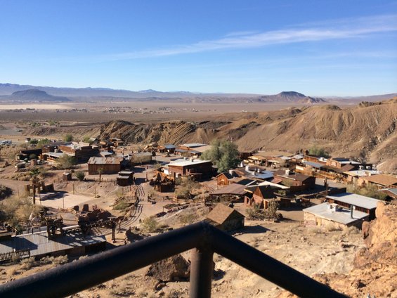 View of an old western town with wooden buildings and dusty streets, set against a desert landscape