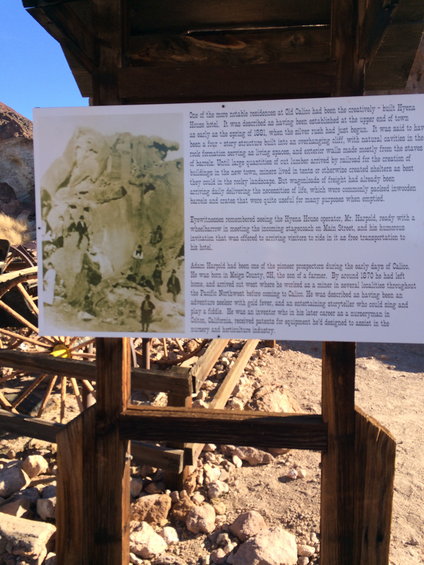 Informational sign with historical photo of people and buildings in a rocky landscape
