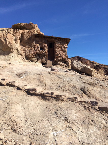 Stone structure built into a rocky hillside under a clear blue sky