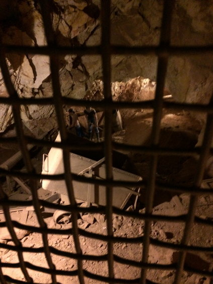 Mine cart in a cave, viewed through a grate