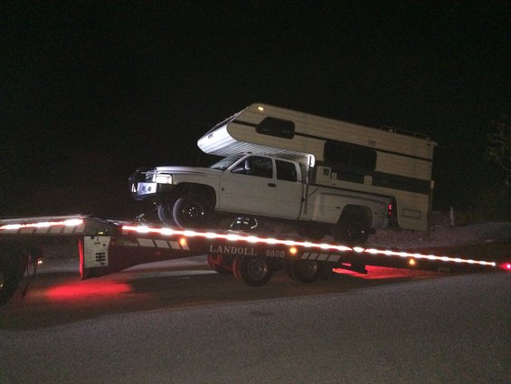 White pickup truck with camper shell loaded onto a Landoll 660B flatbed trailer at night