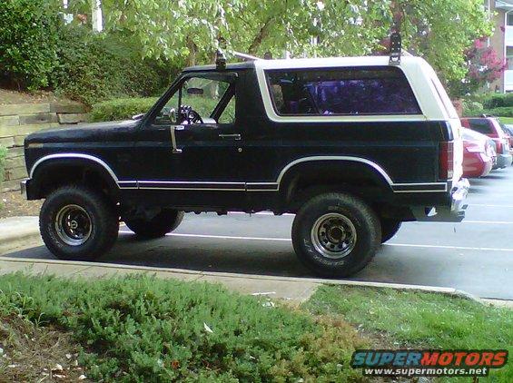 Black and white Ford Bronco, lifted, side view, parked in lot