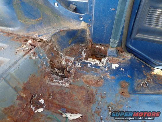 Blue interior floor with extensive rust damage and missing metal
