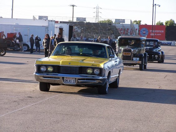Yellow and silver Mercury Cougar with license plate OMLAS 1, followed by older cars