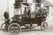 1914 Ford Model T - A 1914 Ford Model T taxi is seen with its driver and two passengers, identified by a sign on top.