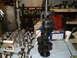 1967 Ford Mustang - Engine parts, including a crankshaft and several pistons, are displayed on a workbench in a garage setting.