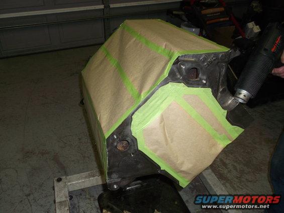Engine block masked with paper and green tape, heat gun in hand