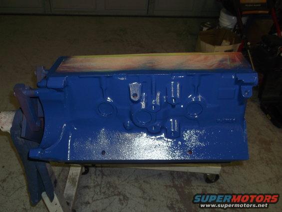 Blue painted engine block on a stand, with tape on top edge
