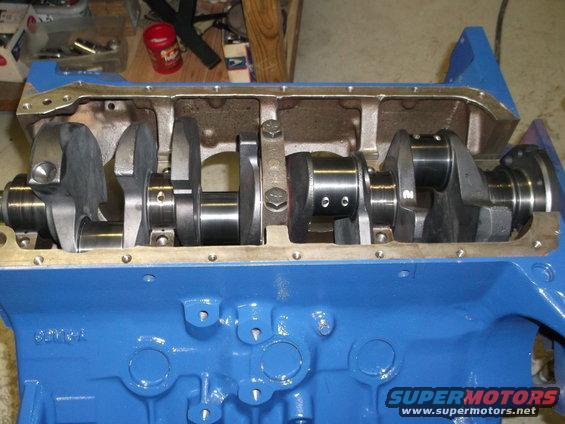 Close-up of a blue engine block with a crankshaft and connecting rods installed