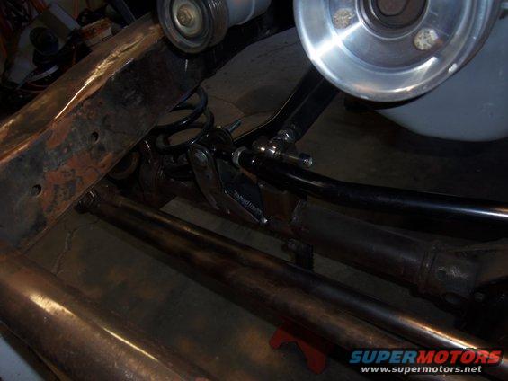 Close-up of rusty frame and suspension parts, including a coil spring and shock absorber