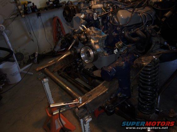 Engine and suspension parts on jack stands, Supermotors logo visible