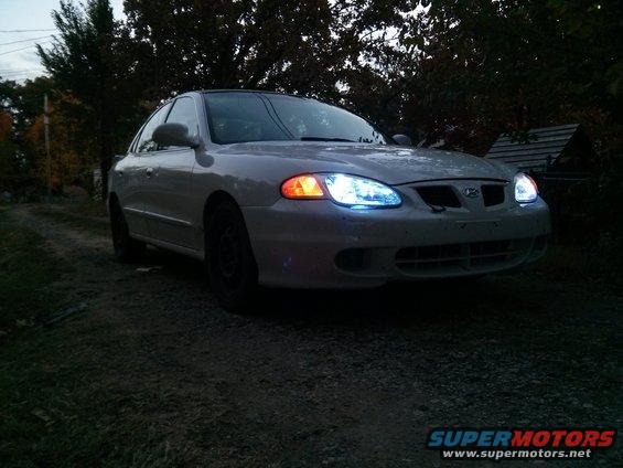 White Hyundai Elantra with aftermarket headlights parked on a gravel driveway