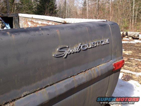 Dark gray 1970 Ford F-250 Sport Custom tailgate with rust and a red taillight
