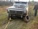 1970 Ford F-250 - Ford truck stuck in mud with a flat tire and a tow strap attached.