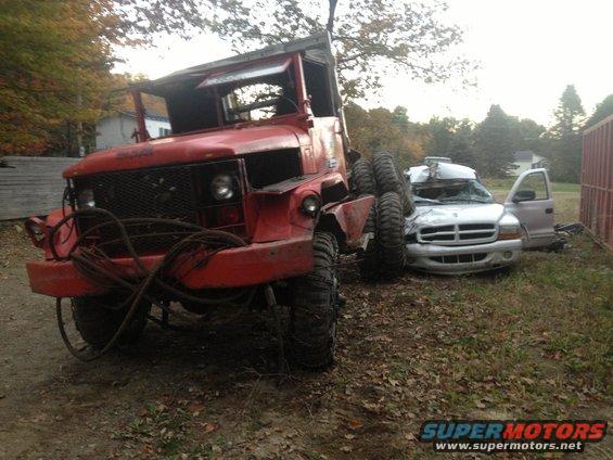 Big red truck parked next to a wrecked white SUV with its door open