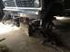 1970 Ford F-250 - A mechanic works on the front suspension of a black Ford F-Series truck, which is elevated on blocks and a jack.