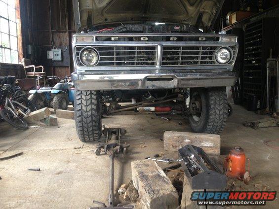 Front view of a 1973 Ford F-Series truck with hood open, undergoing repairs