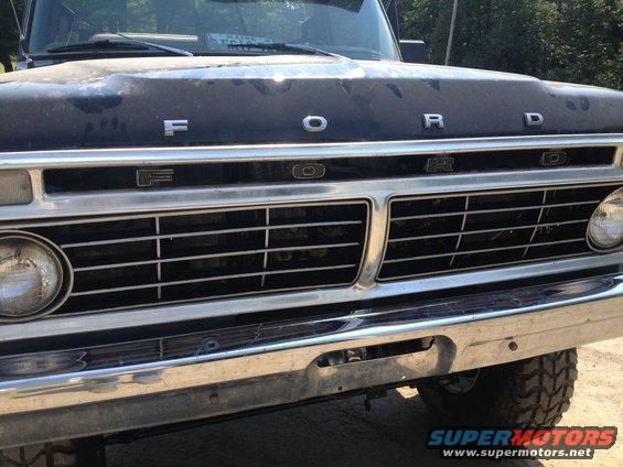 Front of a dark blue Ford truck, showing the grille and hood emblem