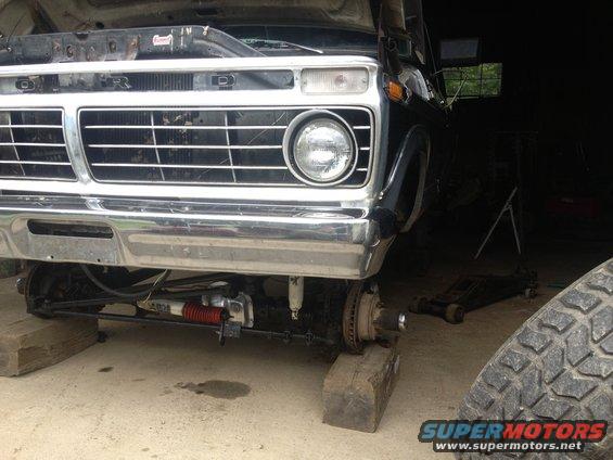 Black Ford truck front end with chrome grille and bumper, raised on blocks with front wheels removed