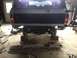 1970 Ford F-250 - Pickup truck in a garage, undergoing repairs with the rear bumper removed and the vehicle elevated on blocks.