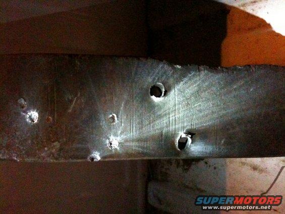 Metal beam with several drilled holes and some surface scratches