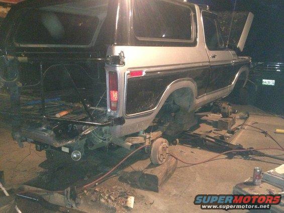 Two-tone Ford Bronco rear end elevated on blocks, undergoing repairs