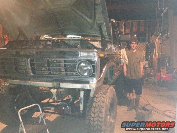 Guy standing next to a lifted 1973 Ford F-Series truck with the hood up