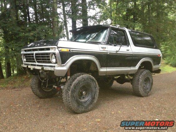 Black and silver lifted Ford Bronco with off-road tires and roof-mounted lights, viewed from the front three-quarter angle
