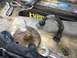 1970 Ford F-250 - Close-up of damaged automotive parts, including a bent metal bracket and a fractured mounting plate, resting on a surface near a car batter…