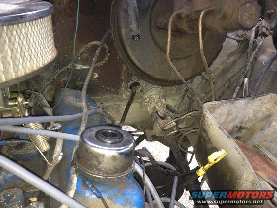Close-up of engine bay with air filter, carburetor, brake booster, and various hoses and wires