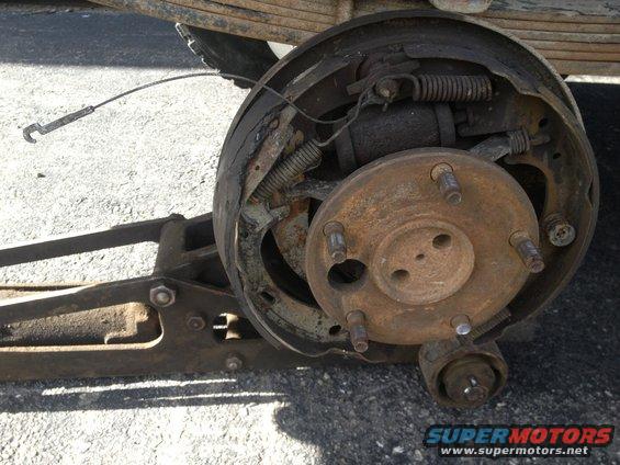 Rear drum brake assembly with rusted components and a detached brake shoe