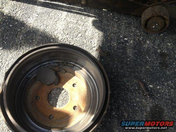 Close-up of a damaged brake drum with pieces of brake shoe material inside