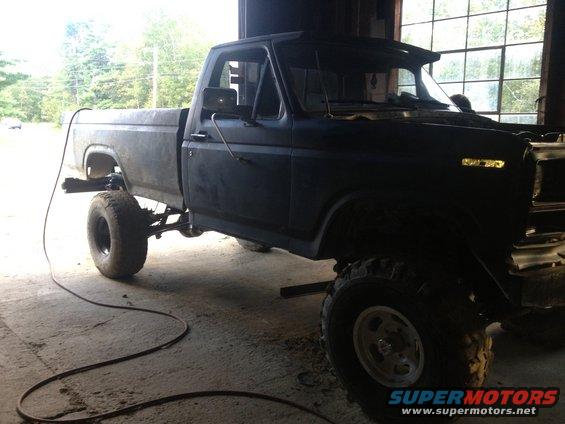 Black Ford pickup truck, lifted with large tires, inside a garage