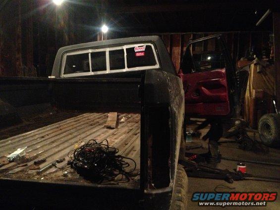 Truck bed with wiring, red interior visible, parked indoors