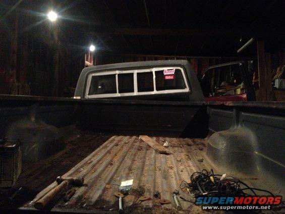 1970 Ford F-250 truck bed with a dark camper shell, showing a red sticker on the rear window
