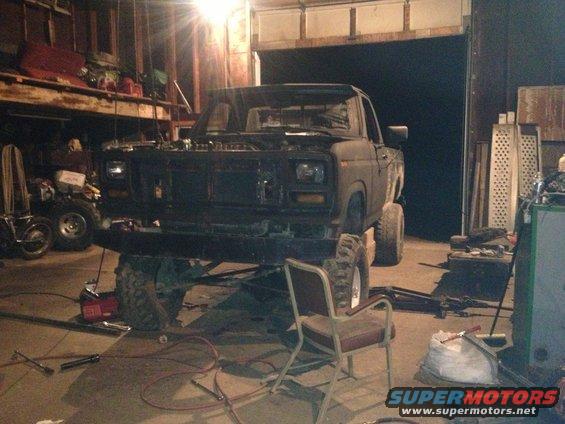 Lifted truck in garage, front view, dark color