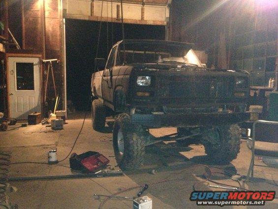 Lifted pickup truck with aftermarket grille and square headlights, in a garage