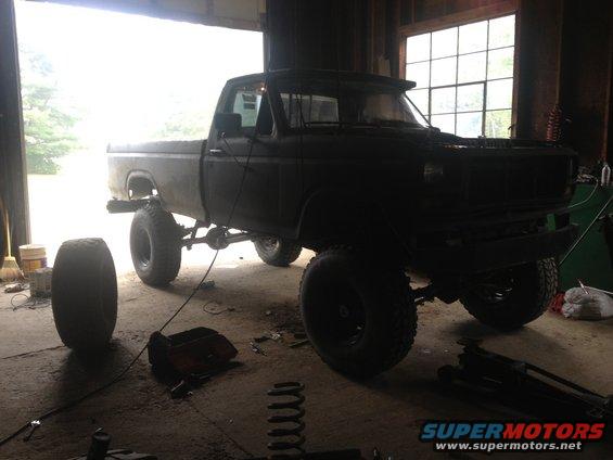1970 Ford F-250 pickup truck with lifted suspension and large tires, parked inside a garage