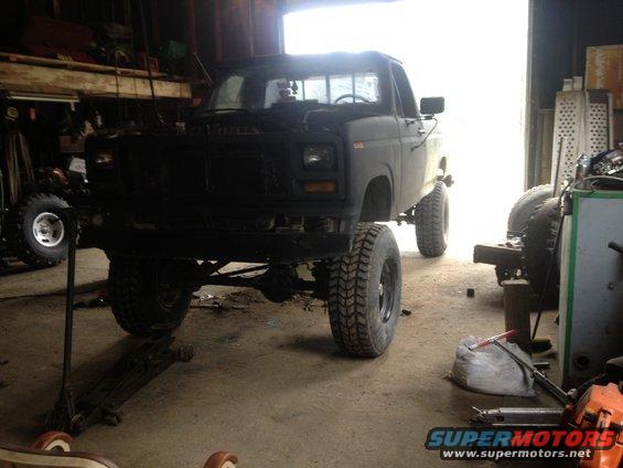 Black lifted pickup truck in a garage, possibly undergoing repairs