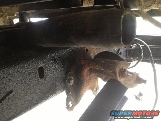 Close-up of rusty underbody suspension part with large pipe