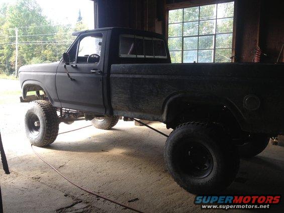 Pickup truck with lifted suspension and large tires, parked inside a garage
