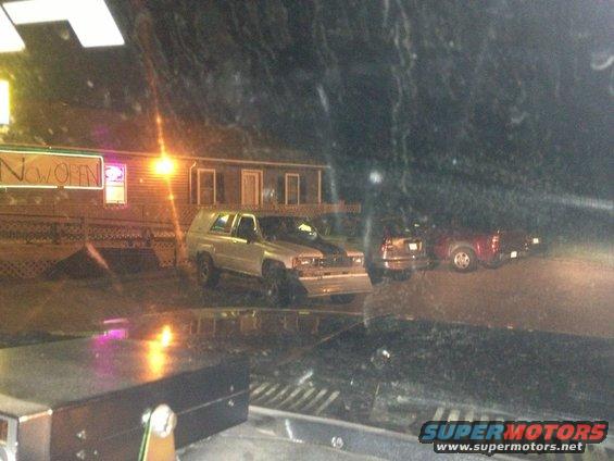 Silver SUV with black racing stripes parked at night, front bumper modified