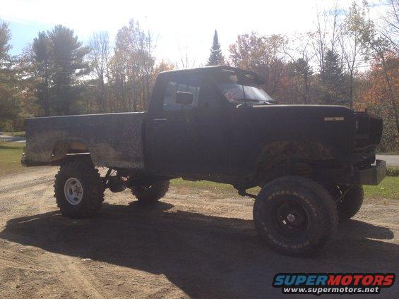 Black pickup truck with lifted suspension and large tires, viewed from the side
