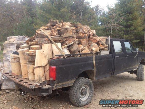 Black pickup truck side view loaded with firewood