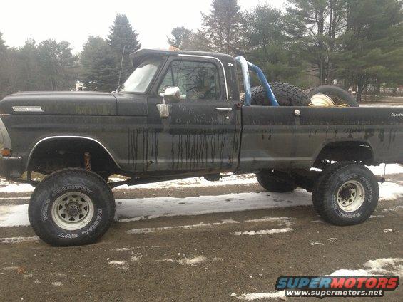 1970 Ford F-250 pickup truck, lifted with large tires, roll bar in bed, black paint
