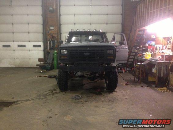 Front view of black pickup truck with custom bumper and lifted suspension