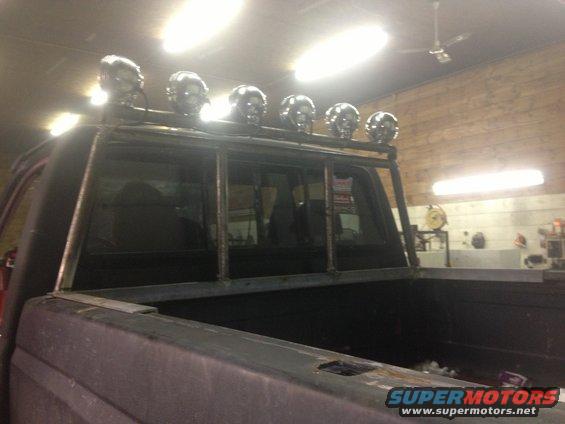 Truck bed with custom metal rack holding five skull-shaped lights above the cab window