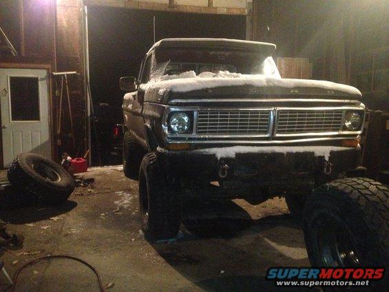 1970 Ford F-250 truck with snow on the hood and roof, parked in a garage