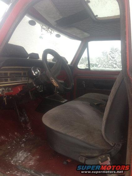 Interior of a 1970 Ford F-250 with a red dashboard and cloth seat